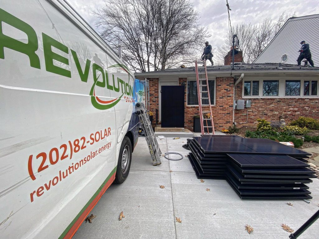 Revolution Solar van outside of brick home with solar panels ready for installation